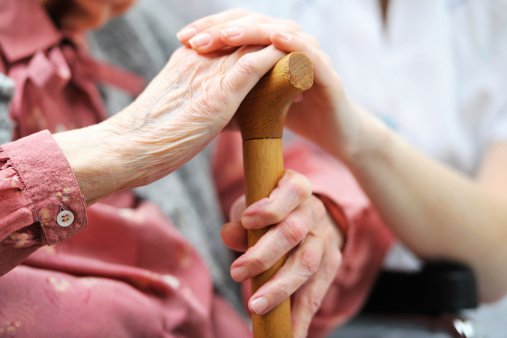 Elderly woman in a Nursing Home and her Caregiver hold hands