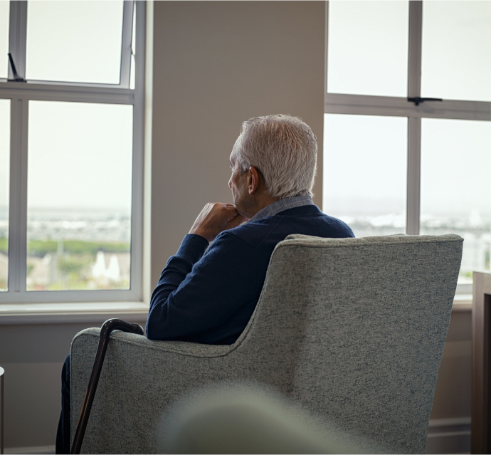 Man alone staring out the window of a nursing home, signifying possible nursing home neglect