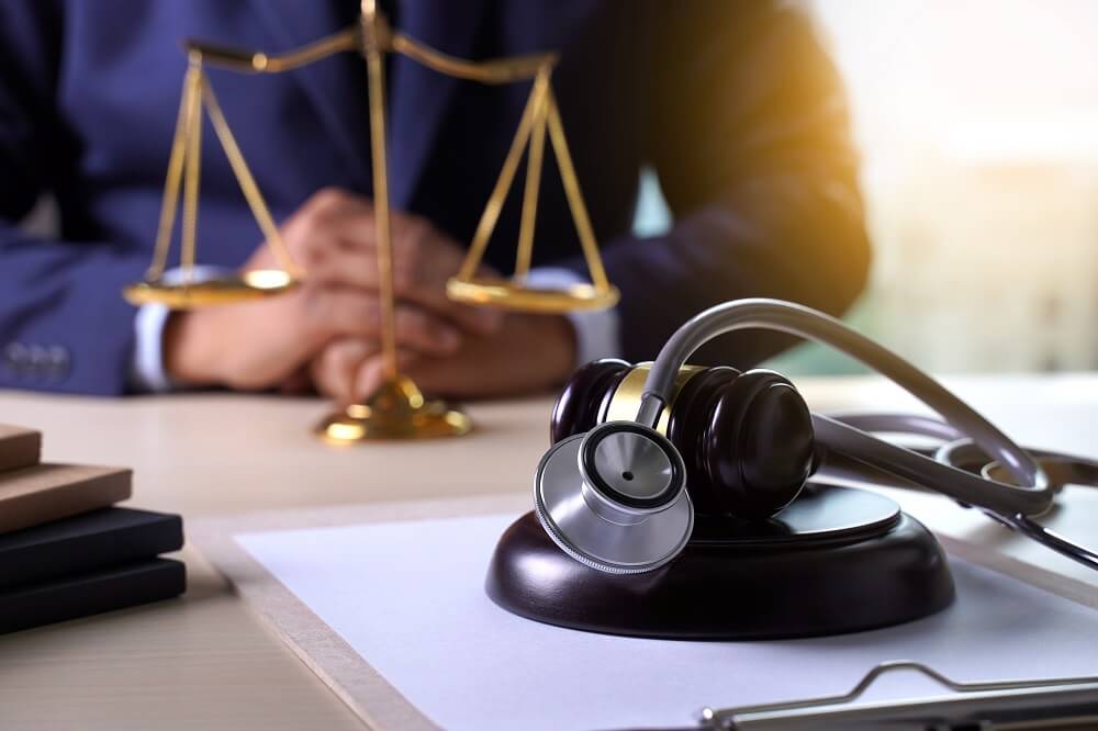 Medical malpractice lawyer with scales of justice, gavel, and stethoscope symbolizing legal action for medical negligence cases.