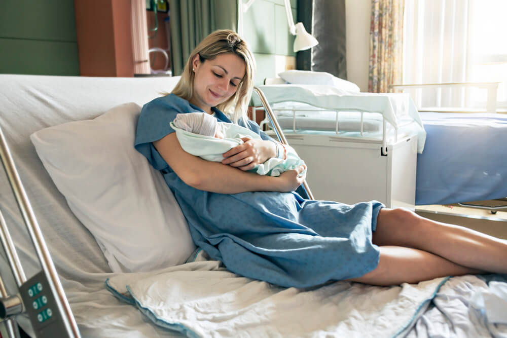 Mother holding newborn in hospital after breech birth delivery