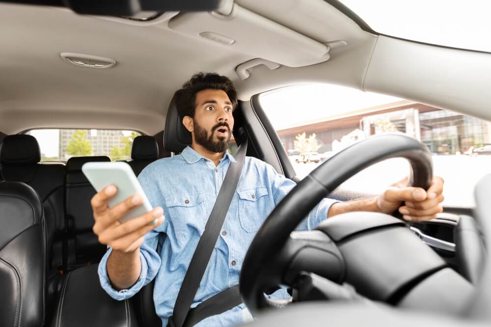 Shocked driver holding phone behind the wheel, illustrating dangers of distracted driving accidents in Chicago