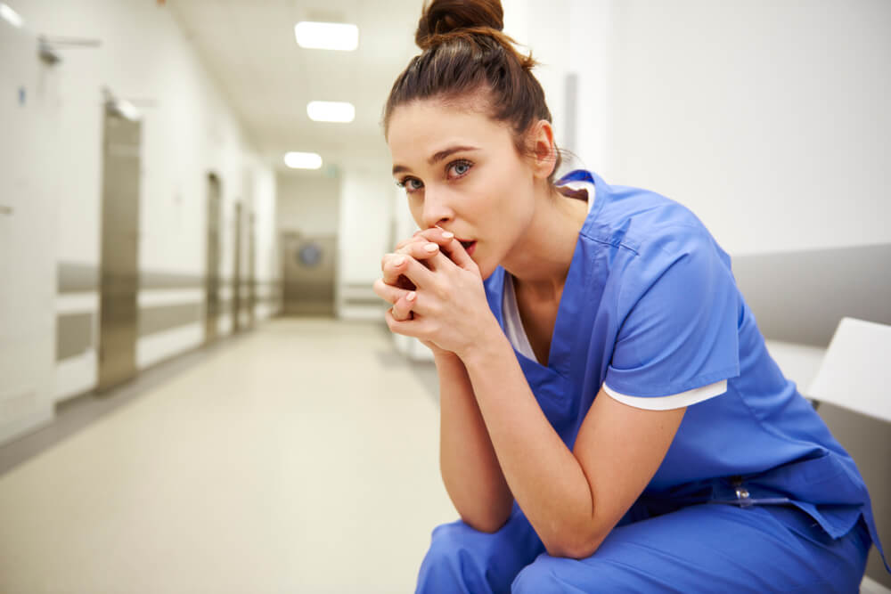 Worried nurse in hospital hallway symbolizing potential nursing negligence and the emotional toll of malpractice claims